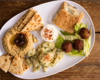 Fresh field greens with quinoa, cucumber, feta, Kalamata olives, red onion, sesame seeds, and crispy falafel, all tossed in a zesty lemon basil vinaigrette. Perfect for group catering.